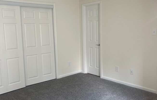 a bedroom with two doors and a carpeted floor