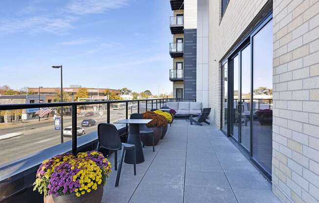 A balcony with a table and chairs overlooking a street.