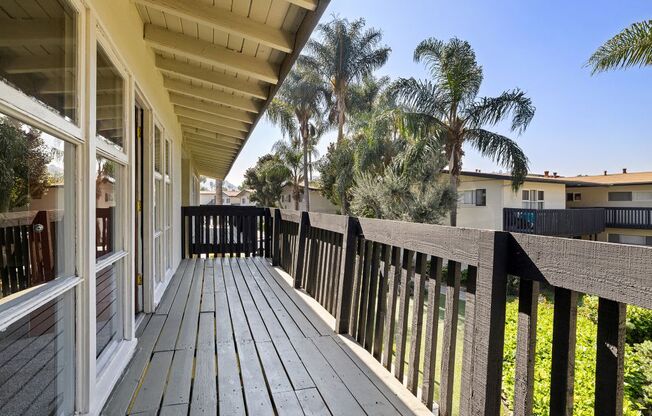 A wooden deck with a railing and a house in the background.