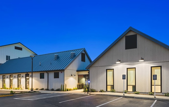 A building with a blue roof and white walls with a parking lot in front.