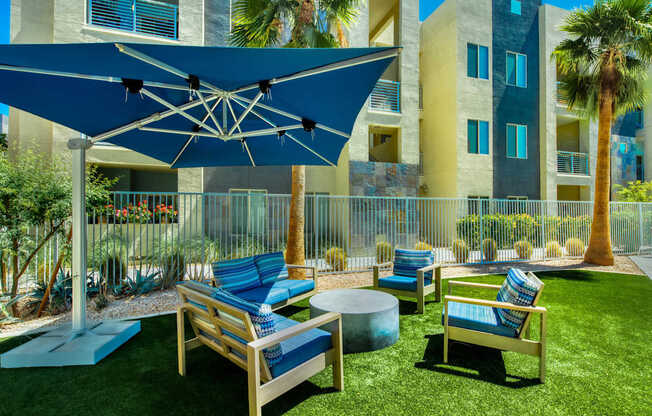 A blue umbrella shades a set of outdoor chairs.