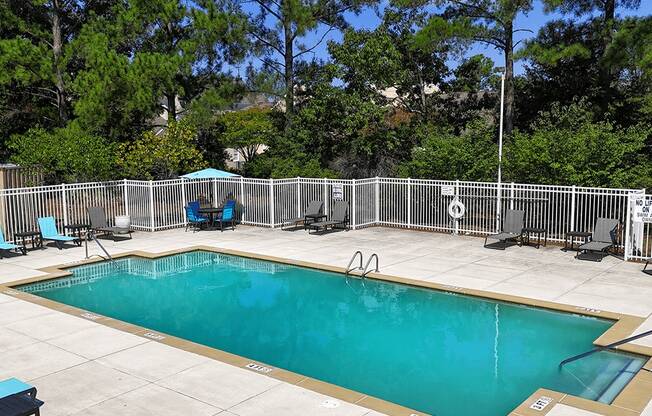 A small pool surrounded by a fence and trees.
