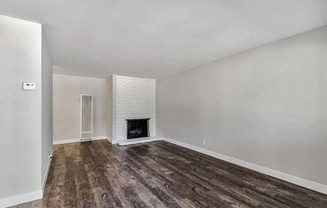 A room with a fireplace and wood flooring.