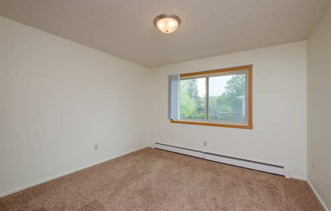 an empty living room with carpet and a window. Fargo, ND Country Club Apartments.