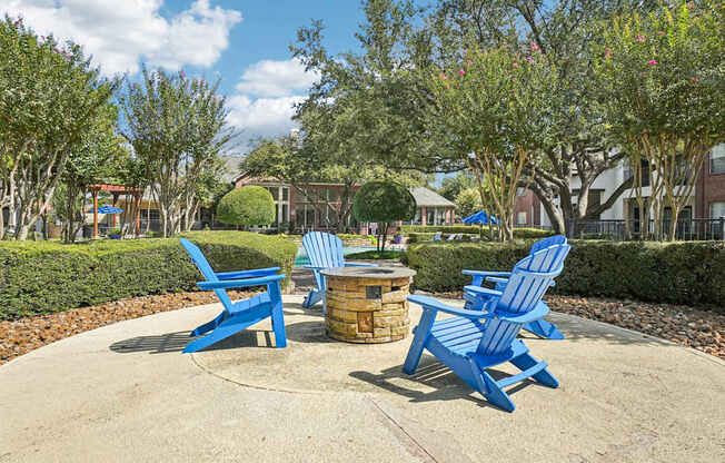 A park with blue chairs and a fire pit.