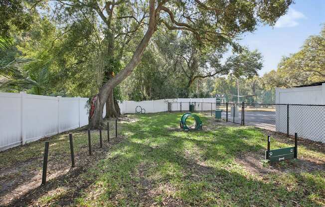 A playground with a swing set and a tree in the middle of a grassy area.