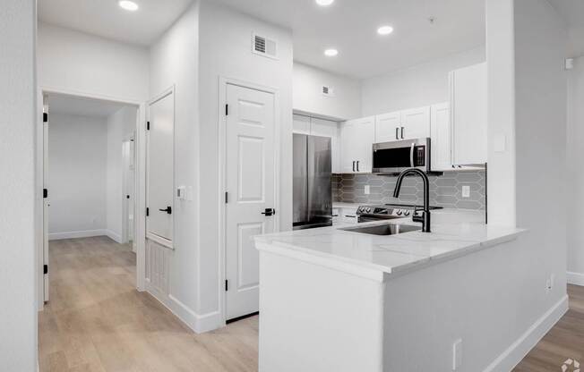 A white kitchen with a sink and a microwave.