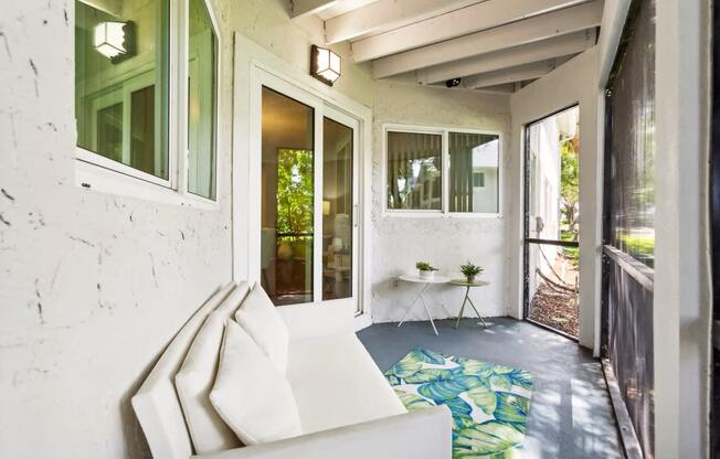 a porch with a white couch and a table on a rug