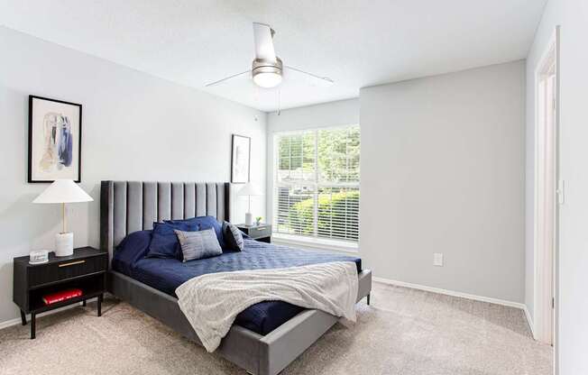 A bedroom with a bed, nightstand, and window.