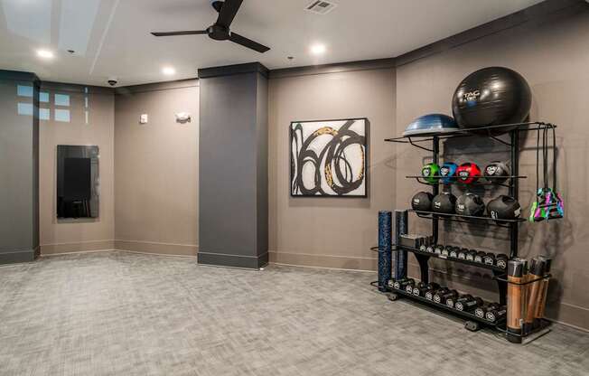 a workout room with a large ball and a rack of weights