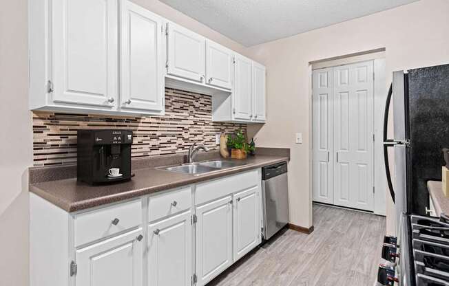 A kitchen with white cabinets and a black refrigerator.