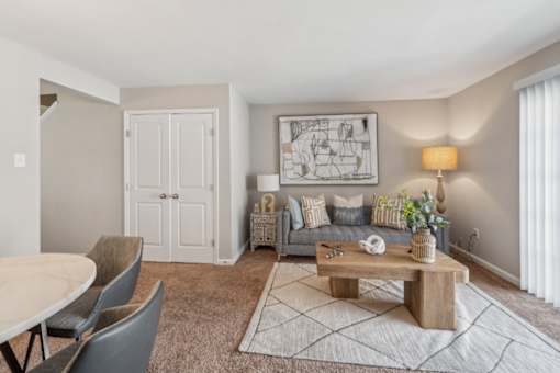 A living room with a grey sofa, a wooden coffee table, and a grey rug at Staples Mill Townhomes Apartments, Richmond, VA, 23228