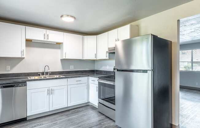 an empty kitchen with stainless steel appliances and white cabinets