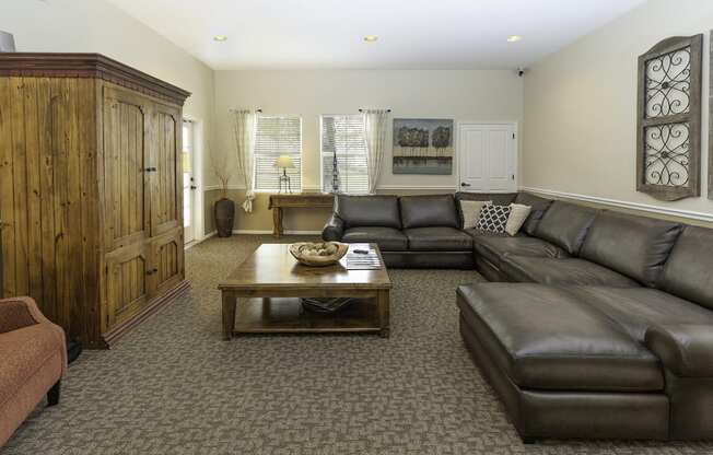 A living room with a brown leather couch and a wooden cabinet.