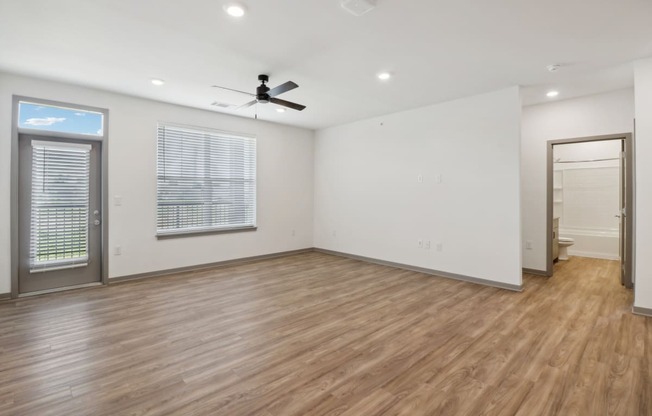 an empty living room with white walls and a ceiling fan at The Depot in The Depot Raymore, MO 64083