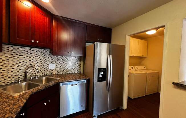 A kitchen with a refrigerator, sink, and cabinets.