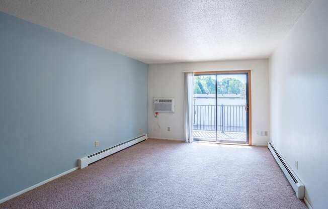 an empty living room with a door to a balcony. Fargo, ND Betty Ann Apartments