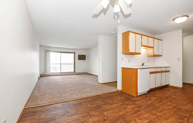 an empty living room and kitchen with wood flooring and a window .Anoka, MN Dellwood Estates