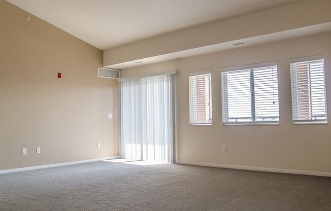 an empty room with a sliding glass door and three windows