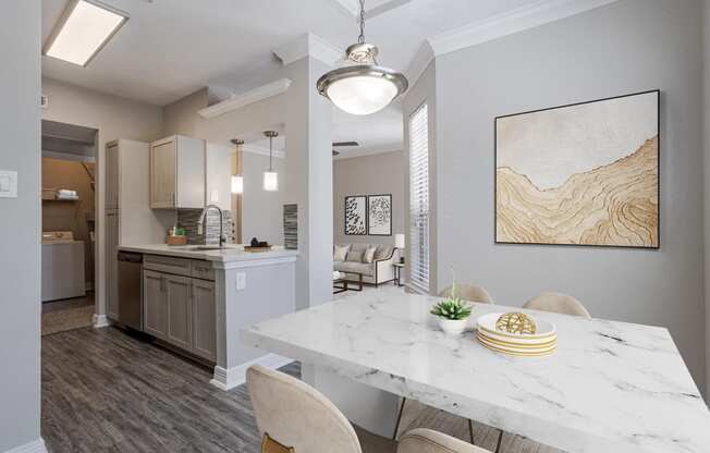 Pet-Friendly Apartments in Houston, TX – Gramercy Park – an open kitchen and dining room with a marble table and chairs