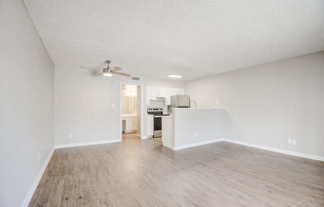 a spacious living room with a kitchen in the background