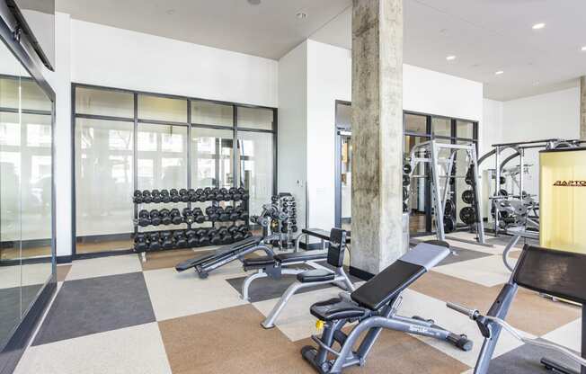 a gym with weights and cardio equipment on the floor and windows