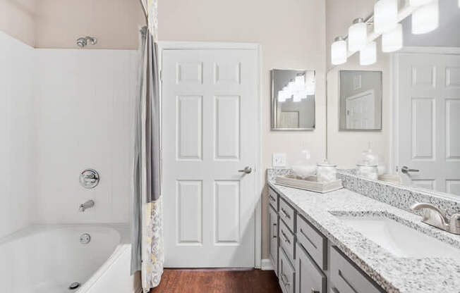 A white bathroom with a tub, sink, and mirror.