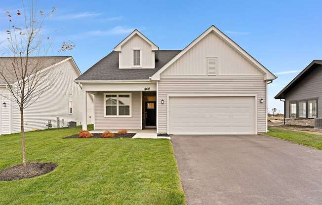 A house with a grey garage door and a black roof.