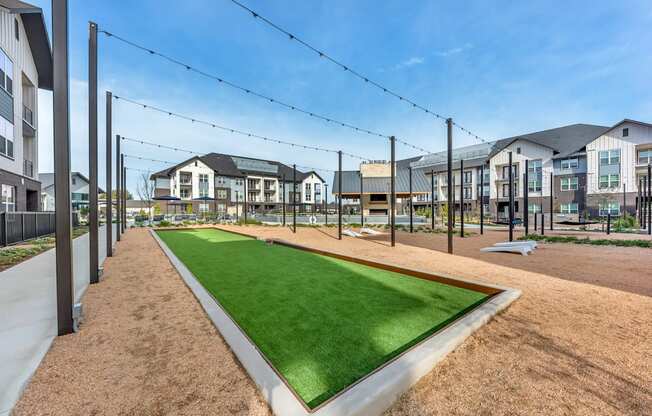 A grassy area in front of apartment buildings with a clear blue sky.