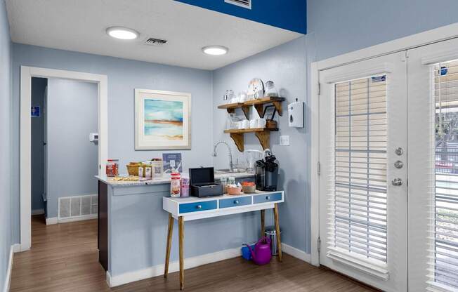 A kitchen area with a table and a shelf with various items on it.