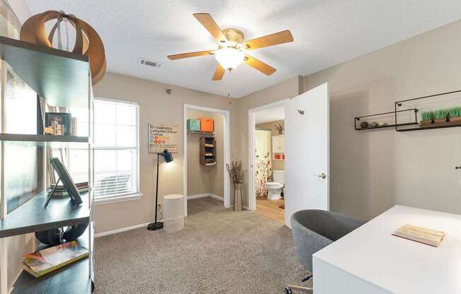 A room with a ceiling fan and a white table with a book on it.