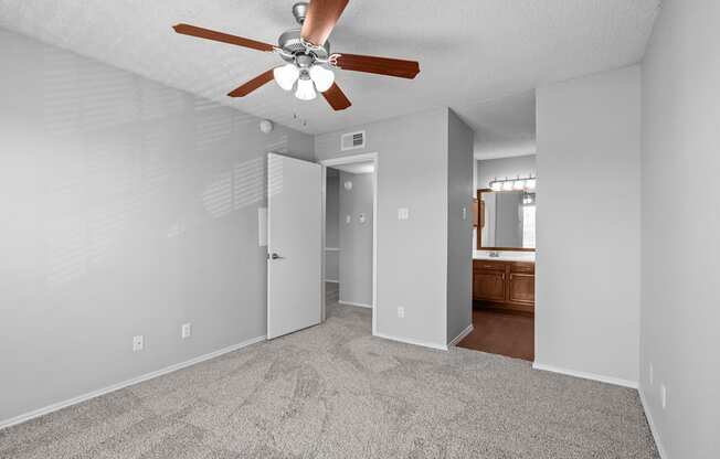 A room with a ceiling fan and carpeted floor.