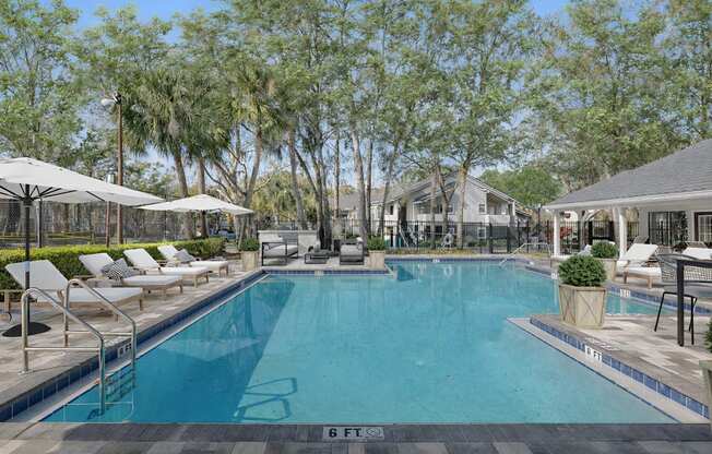 A large swimming pool surrounded by trees and lounge chairs.
