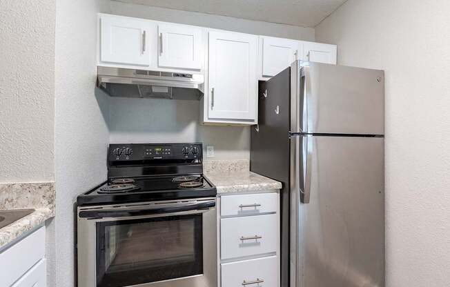 A kitchen with a stove, refrigerator, and cabinets.