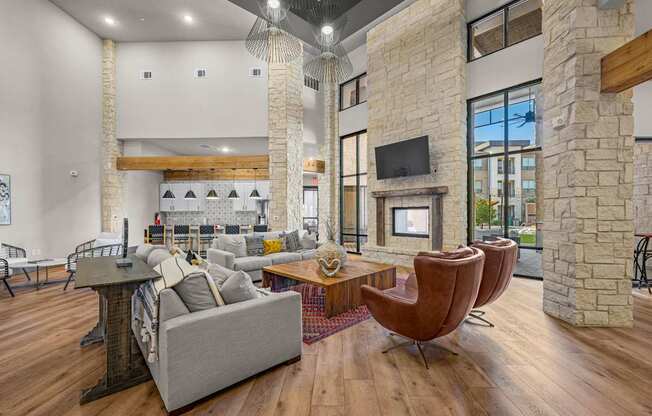 A living room with a grey couch, a brown chair and a stone fireplace.