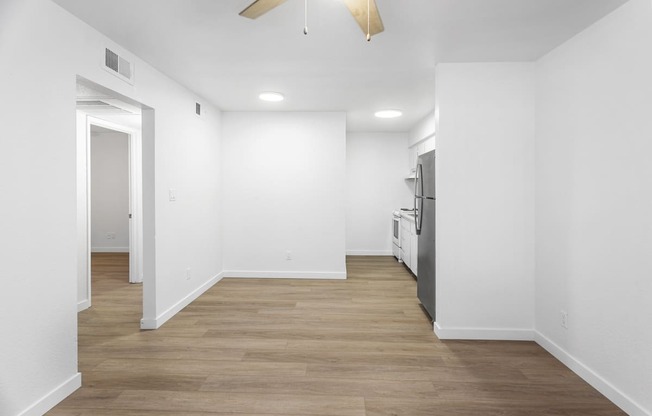 a renovated living room and kitchen with white walls and wood floors