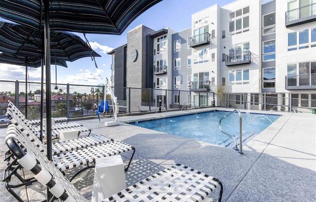 a pool with lounge chairs and umbrellas at Circa Central Avenue Apartments