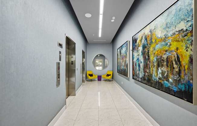 the hallway of a building with paintings on the wall and doors