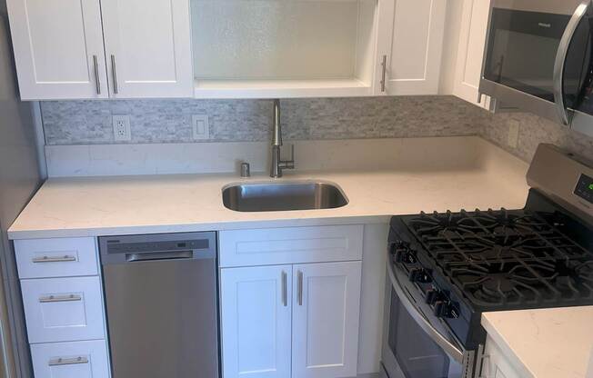 A kitchen with white cabinets and a black stove top.
