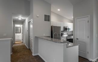 a kitchen with a granite counter top and a stainless steel refrigerator