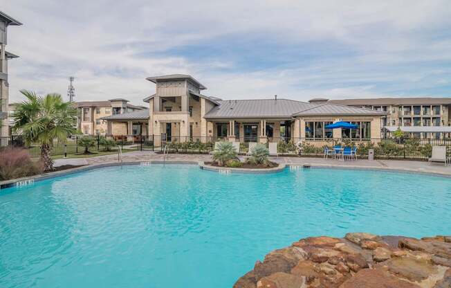 A large swimming pool in front of a resort-style building.