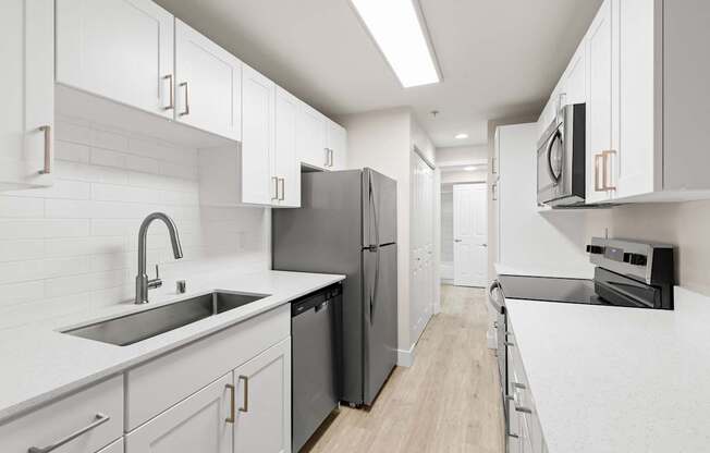 A modern kitchen with white cabinets and a black fridge.