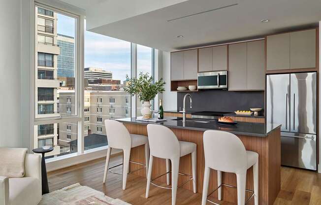 A modern kitchen with white chairs and a view of the city.