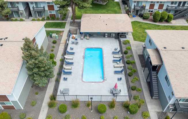 A swimming pool surrounded by a concrete patio and a covered area at Wildflower Apartments in Kennewick, WA..