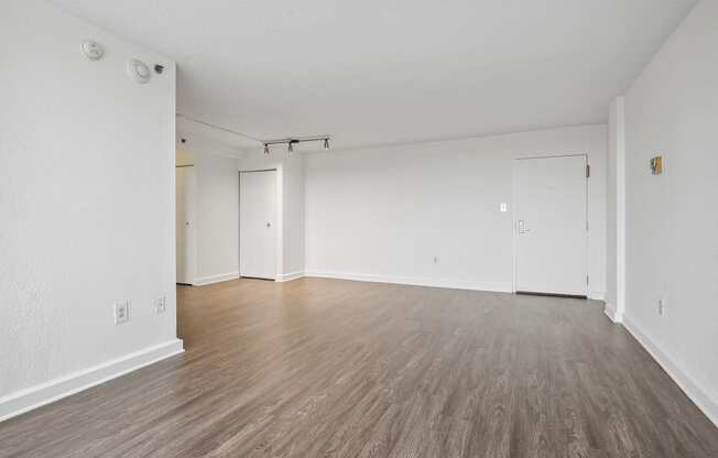 an empty living room with wood floors and white walls