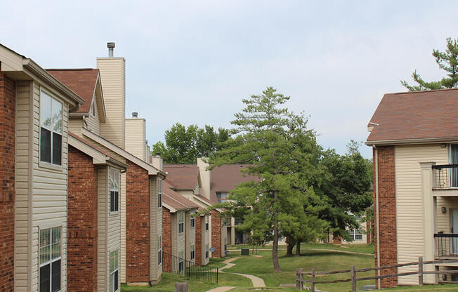 an apartment complex with a grassy area and trees