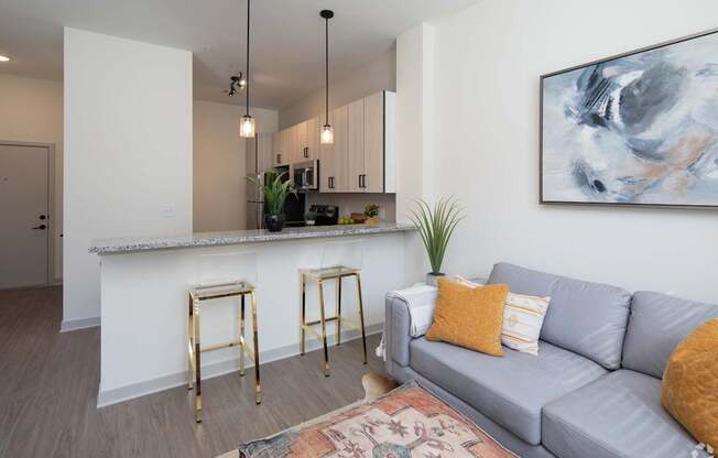 A living room with a grey couch and a bar area.