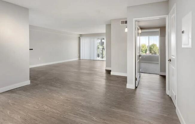 an empty living room with white walls and wood floors