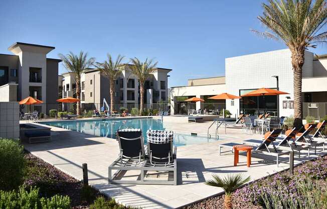 A pool area with chairs and umbrellas in front of a building.