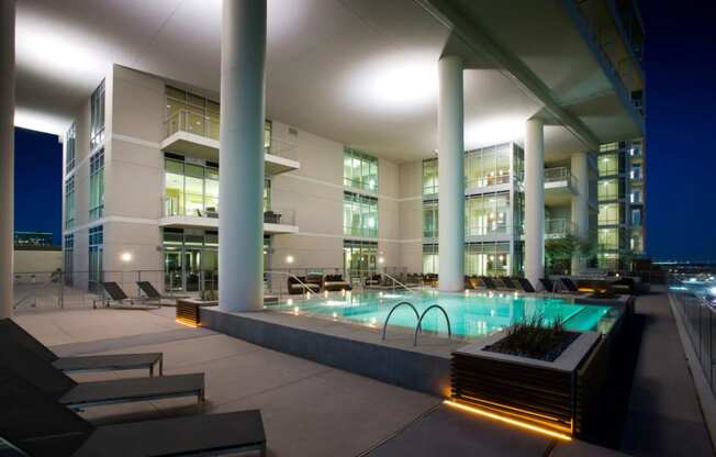 Apartments for Rent in University Park, TX - Heights at Park Lane - Pool with City Views, Lounge Chairs, and Building.